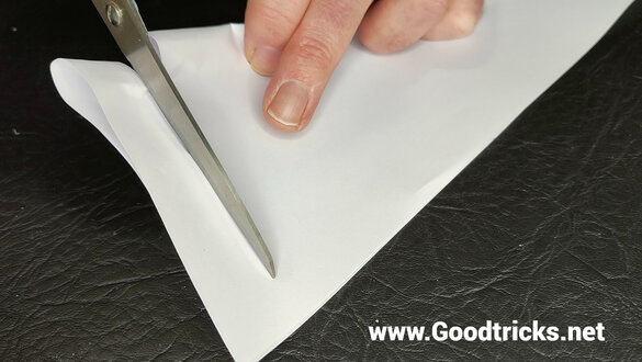 Cutting through a sheet of paper with scissors in preparation for a magic trick.