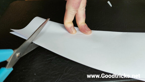 Cutting a sheet of paper with scissors to make a magic trick prop.