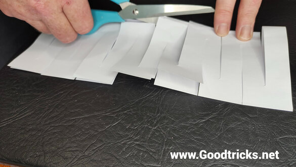 Cut along the center folded side of a sheet of paper with scissors to make a magic trick gimmick.